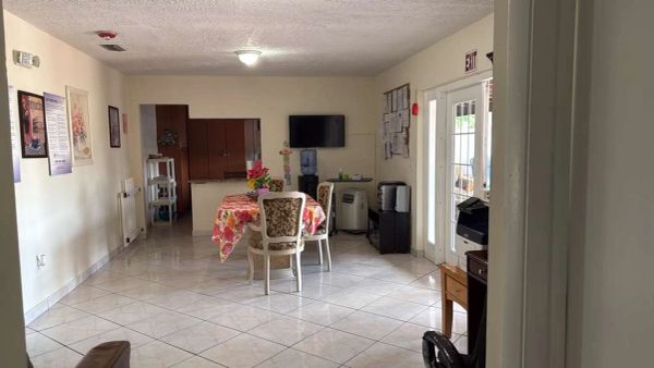 A simple, clean dining area with a floral tablecloth and chairs.