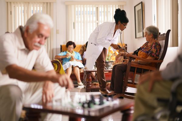 Healthcare worker checking elderly patient's blood pressure.
