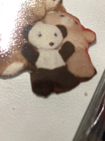 A close-up of a small panda-shaped cookie or biscuit on a white surface.