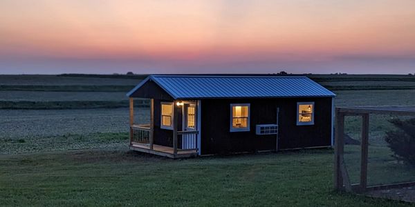 Small house glowing warmly at dusk in a peaceful rural setting.