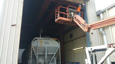 Worker on elevated platform inspecting a large industrial container.