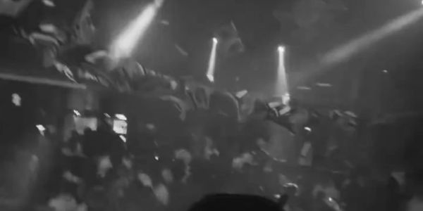 Silhouette of a DJ performing to a crowded nightclub with dynamic lighting and decorations.