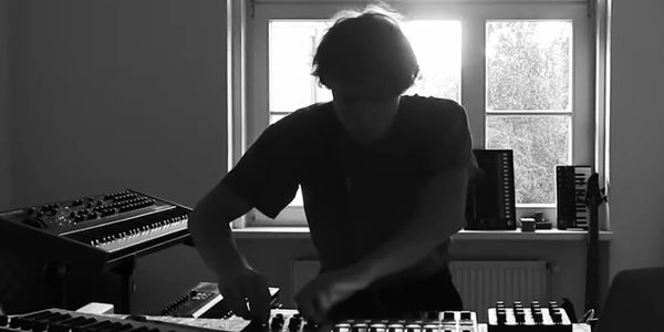 Person working with music equipment in front of a window with bright light.