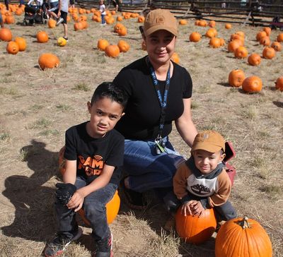 A parent and children in a pumpkin field.