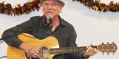 a man plays his guitar and sings into the microphone. 