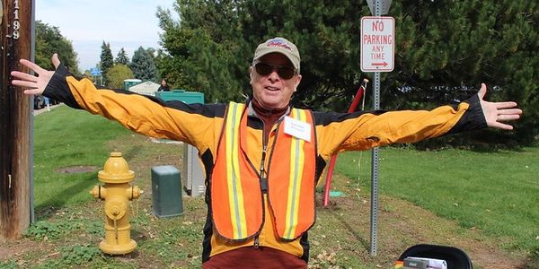 A Friends of the Library and Museum with arms outstretched stands at the outside of the Craft Fair in Littleton.