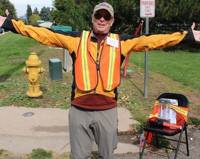 A volunteer with outstretched hands stands at the corner of the Craft Fair in Littleton. 