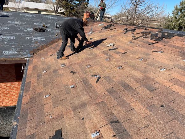 Workers installing new roof shingles.