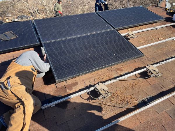 Worker installing solar panels on a rooftop.