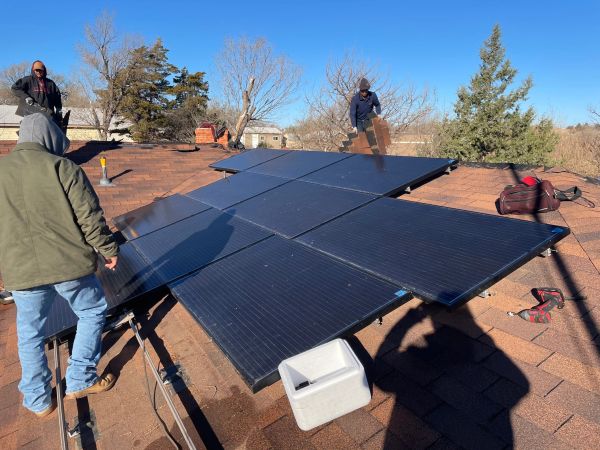 Workers installing solar panels on a roof.