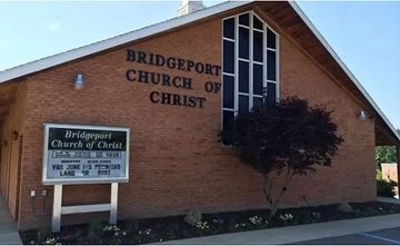 Brick building of Bridgeport Church of Christ with a sign and small tree.