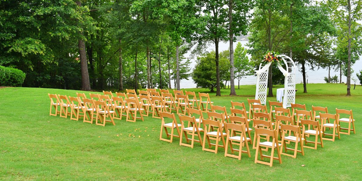 Sillas de madera ordenadas en un césped para una ceremonia al aire libre.