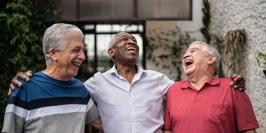 Three elderly men laughing and enjoying each other's company outdoors.