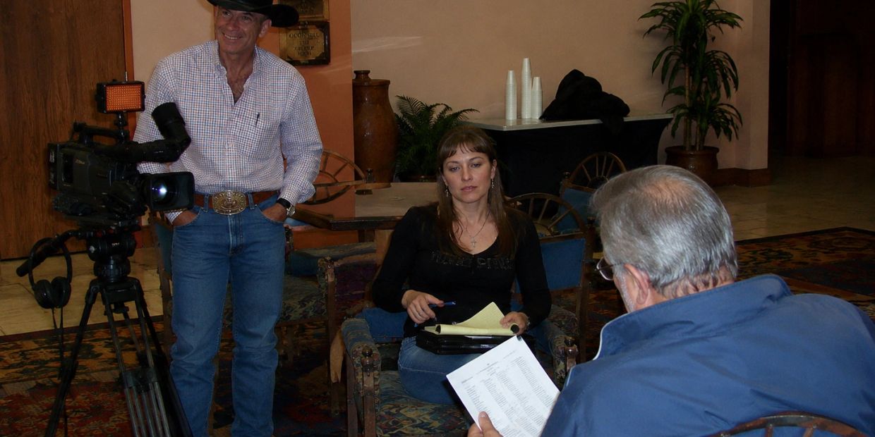 A woman is interviewed while a cameraman records the scene indoors.