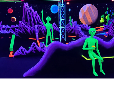 Glowing green aliens in a neon space-themed mini golf course under blacklight.