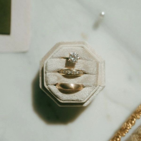 Three rings in a white velvet ring box on a marble surface.