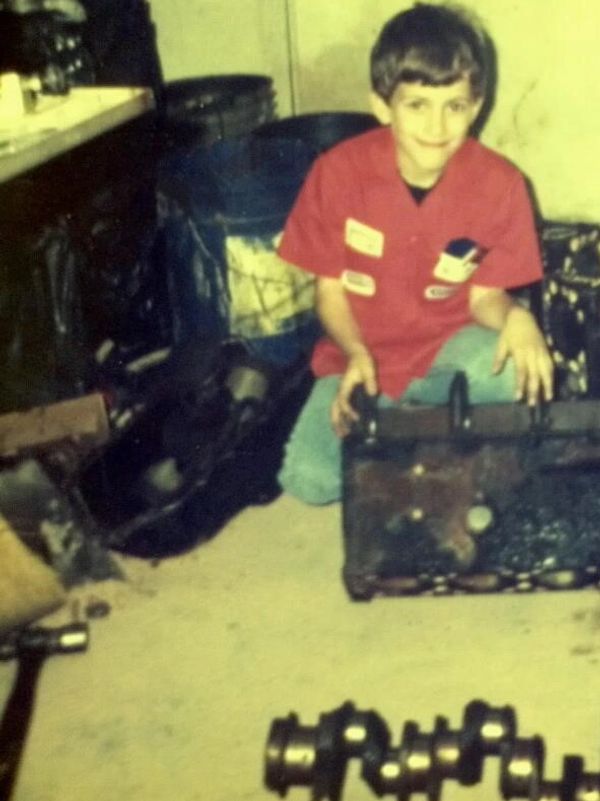 Young boy in a red shirt working with mechanical parts indoors.