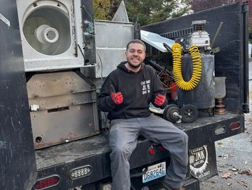 Man sitting on truck tailgate with industrial equipment.