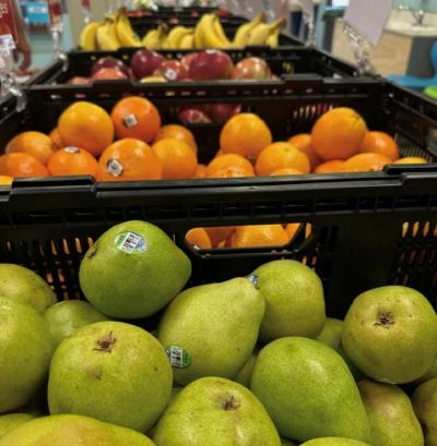 Pears, oranges, apples, and bananas in crates at a market.