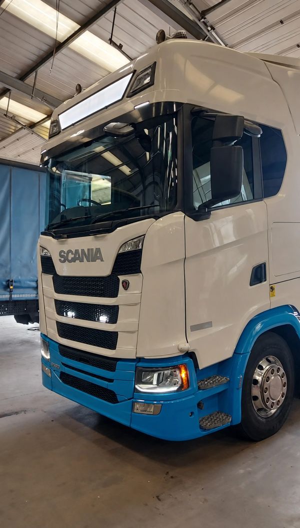 White and blue Scania truck parked inside a warehouse.