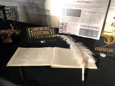 Open guest book with a decorative feather pen on a table.