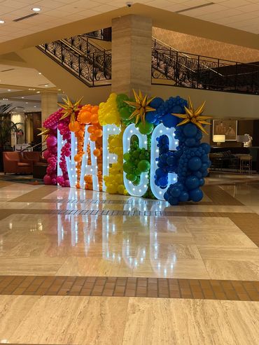 Colorful welcome sign with balloons indoors.