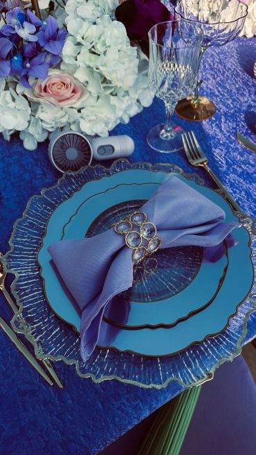 Elegant blue table setting with flowers and glassware.
