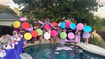 Group celebrates poolside with colorful parasols.