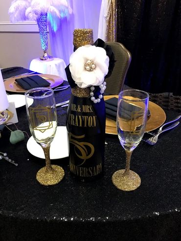 Anniversary champagne bottle with two glasses on table.