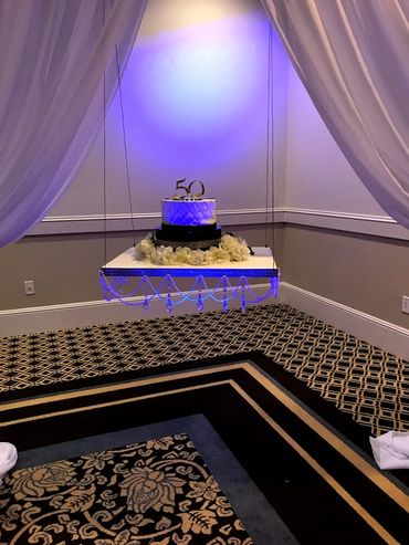 50th anniversary cake suspended on a decorated platform with drapes.