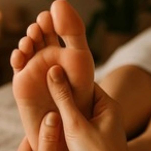 Hand massaging a foot in a relaxing setting.