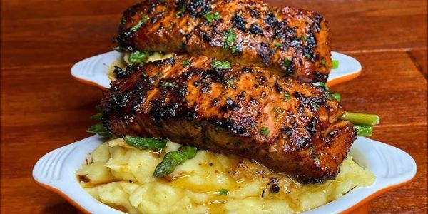 Grilled salmon fillets served on mashed potatoes with asparagus.
