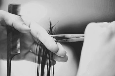 Close-up of hair being cut with scissors and a comb.