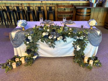 Elegant wedding table decorated with flowers, greenery, and candles.