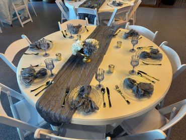 Elegantly set round table with gray-themed decor and floral centerpiece.
