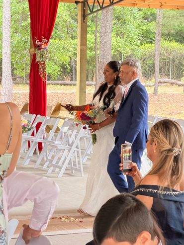 Bride walking down the aisle with an older man at an outdoor wedding ceremony.