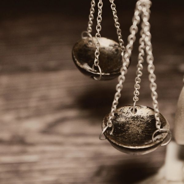 Close-up of metallic balance scale pans hanging by chains.