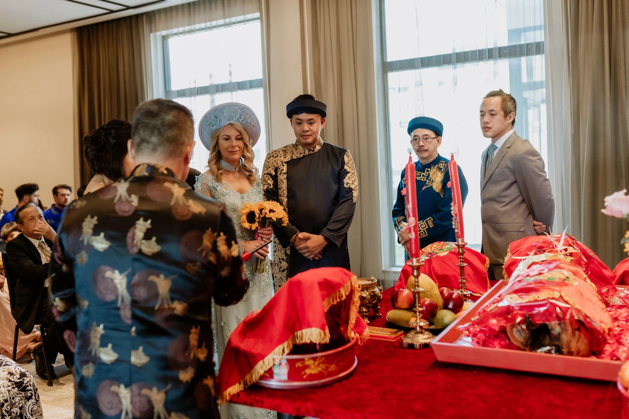 Pierre Nguyen in traditional Vietnamese wedding attire with his wife and surrounded by his family.