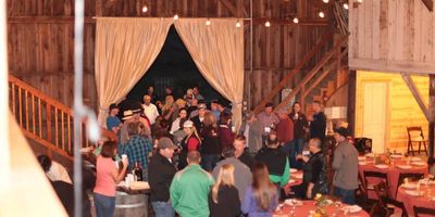 People socializing inside a warmly lit barn with rustic decor.