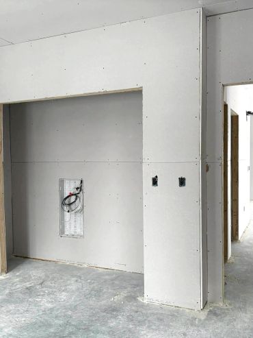 Mur en plaques de plâtre avec installation électrique incomplète.