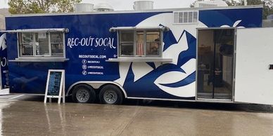 Blue and white Rec-Out SoCal food truck with service windows and open door.