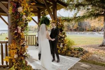 Bride and groom holding hands during outdoor wedding ceremony in autumn.
