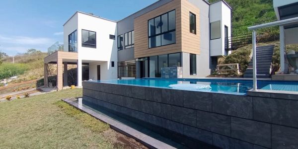 Modern two-story house with a pool and glass windows.