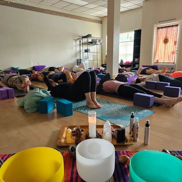 Group doing relaxing yoga with mats and props in a cozy studio.