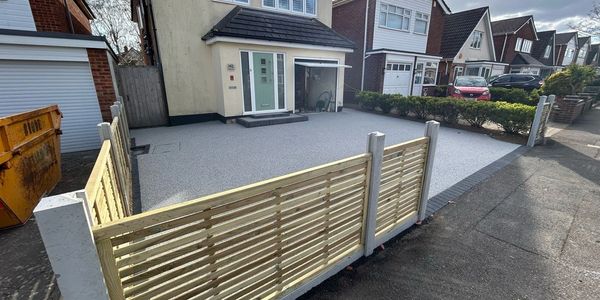 Resin bound driveway with modern slatted timber fencing for added kerb appeal and security.