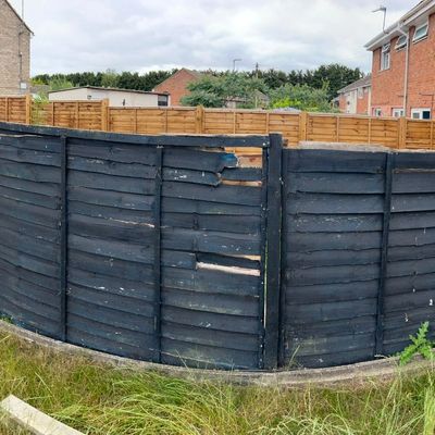 Damaged black fencing with peeling paint and overgrown grass in Huntingdon garden before revamp
