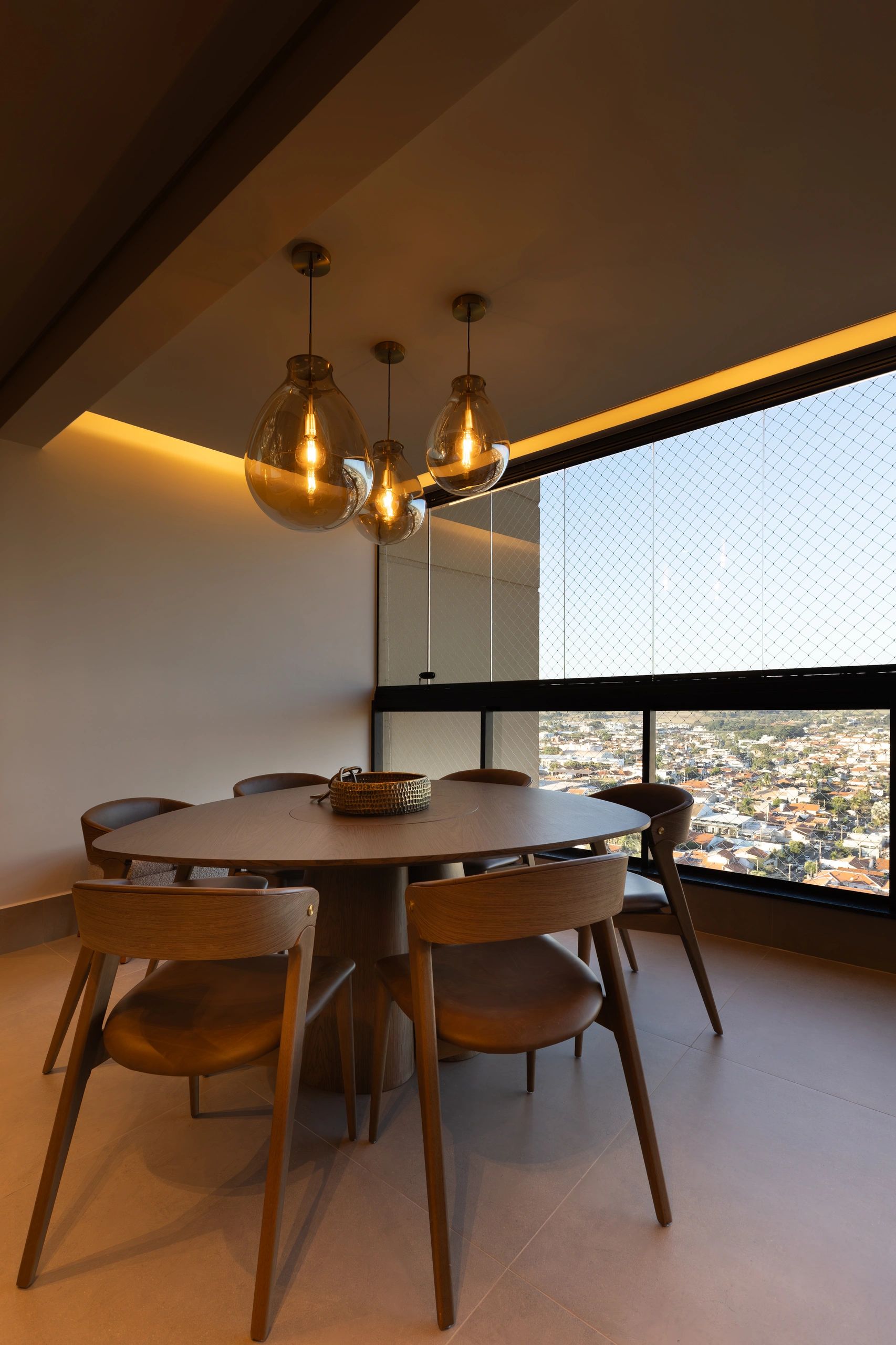 Sala de jantar com luminárias modernas e vista para a cidade.