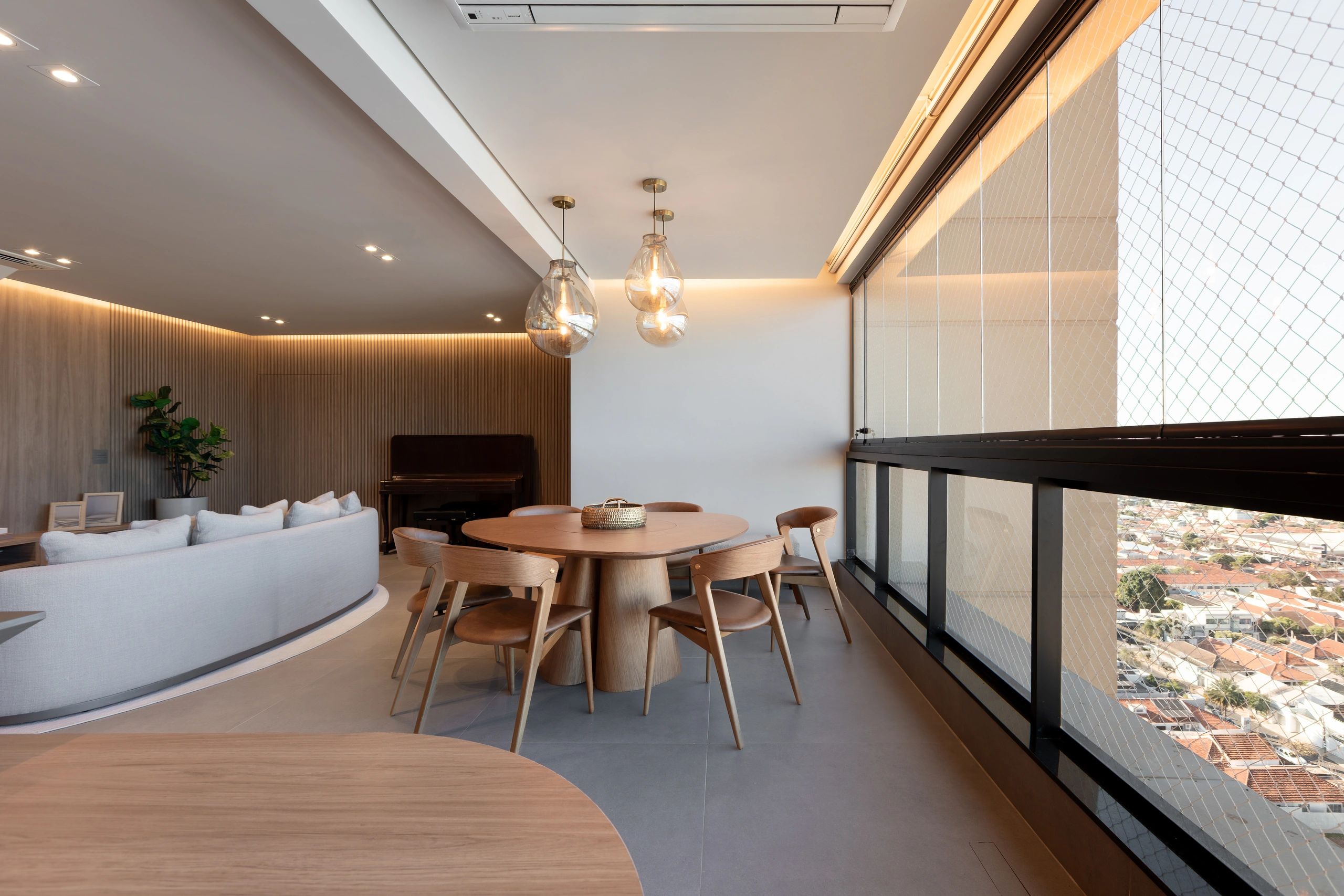 Sala de jantar moderna com mesa de madeira e cadeiras ao lado de varanda.