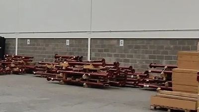 Stacks of wooden logs and planks arranged outside a building.
