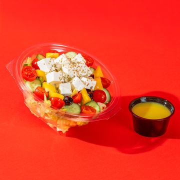 Greek salad with feta cheese and dressing on a red background.